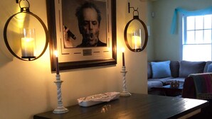 Een eetgedeelte met een donker houten tafel, twee kandelaars en een ingelijst citaat aan de muur.