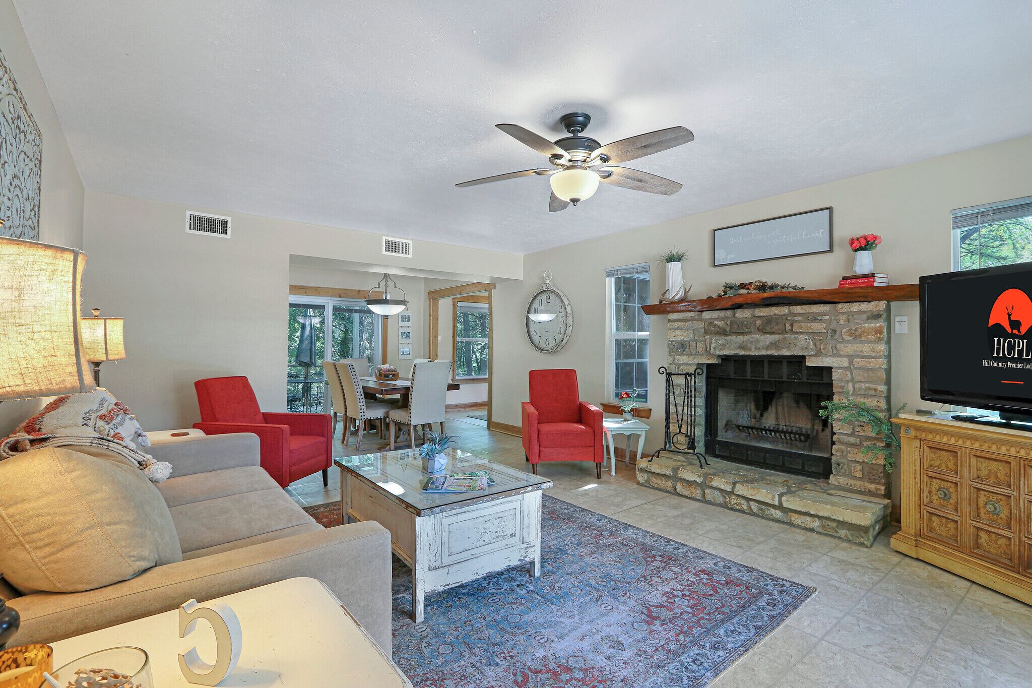 A living room with a fireplace, a ceiling fan, and a television.