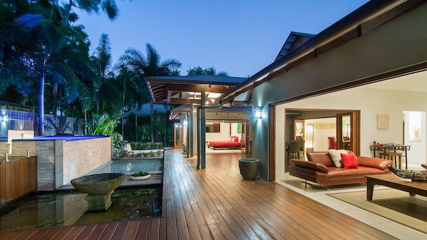 A modern outdoor living area with a wooden deck, a stone basin, and a red sofa.