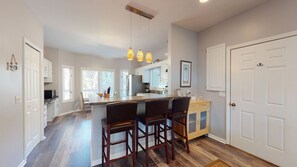 A modern kitchen with a central island, bar stools, pendant lighting, and a large white door.