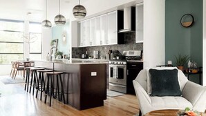 A modern kitchen with a central island, bar stools, and a dining area with a sofa and coffee table. - Urban Oasis | Rooftop Delight | Peloton | RiNo (Denver)