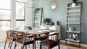 A dining area with a wooden table set for four, a modern chandelier, a mirror, a shelf with glasses, and a globe. - Urban Oasis | Rooftop Delight | Peloton | RiNo (Denver)