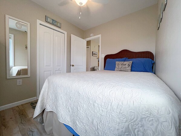 A bedroom with a large bed, two doors, a mirror, and a ceiling light.