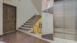 A modern interior with a wooden door labeled '306', a staircase with granite steps, and an elevator. - Treebo Mohit Regency (Bhopal)