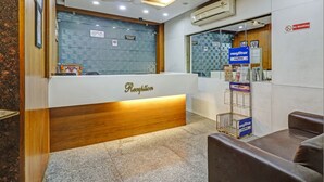 A reception area with a wooden reception desk, a "Reception" sign, a "No Smoking" sign, and a blue sign with text in a non-Latin script. - Treebo Mohit Regency (Bhopal)