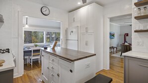 Eine moderne Küche mit weißen Schränken, einer Kochinsel aus Holz und einem eingebauten Backofen.