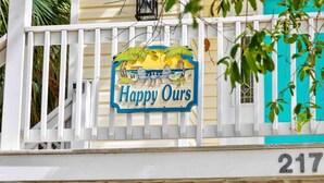 A sign with 'Happy Ours' and the number 217 on a white fence. - Folly Beach Gem: Walk to Beach, Restaurants & Nightlife - Happy Ours (Folly Beach)