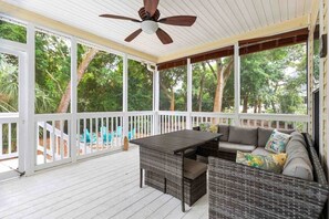 A covered porch with a table and seating, surrounded by white railings and trees. - Folly Beach Gem: Walk to Beach, Restaurants & Nightlife - Happy Ours (Folly Beach)