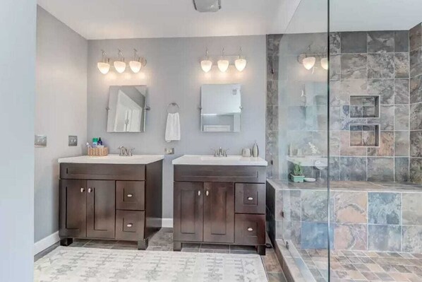 A modern bathroom with two sinks, a large mirror, and a glass shower enclosure. - Folly Beach Gem: Walk to Beach, Restaurants & Nightlife - Happy Ours (Folly Beach)