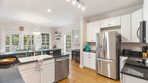 A modern kitchen with white cabinets, stainless steel appliances, and a black countertop. - Folly Beach Gem: Walk to Beach, Restaurants & Nightlife - Happy Ours (Folly Beach)