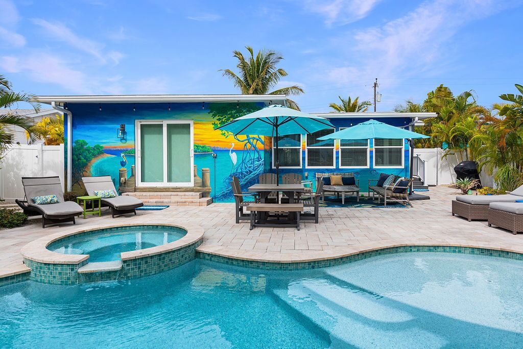 A pool area with a mural, lounge chairs, and umbrellas.
