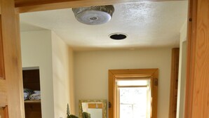Un baño de madera con un lavamanos blanco, un espejo y una ventana.