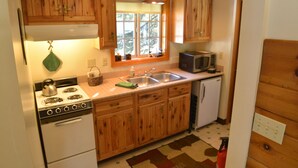 Una cocina compacta con armarios de madera, estufa, microondas y pileta.