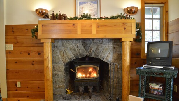 Una chimenea de piedra con un televisor sobre un mueble a la derecha.