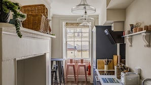 A kitchen with a window, two stools, a toaster, and a hanging light fixture. - Impeccable 4-bed Apartment in Bath (Bath)