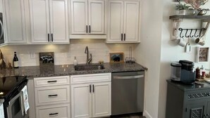 A kitchen with white cabinets, a granite countertop, a dishwasher, and a coffee maker on a cabinet. - Sugar In The Sky - Quiet End Unit w/ Air Conditioning & Work Space (Sugar Mountain)