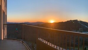 A balcony with a view of a sunset over a mountain range. - Sugar In The Sky - Quiet End Unit w/ Air Conditioning & Work Space (Sugar Mountain)