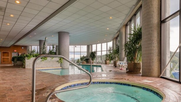 An indoor swimming pool with a tiled floor, a metal pool ladder, and large windows allowing natural light. - Sugar In The Sky - Quiet End Unit w/ Air Conditioning & Work Space (Sugar Mountain)