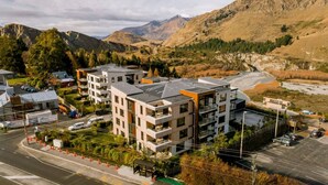 Un bâtiment moderne à plusieurs étages, doté d’un toit plat, entouré d’un parking et bordé par une route.