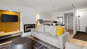Un salon moderne avec un canapé, un pouf et une cheminée.