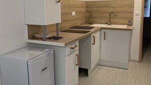 A compact kitchen with white cabinetry, a built-in stove, a sink, and a compact refrigerator. - Maisonette with garden (Mornas)