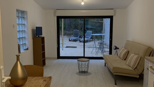 A modern living room with a wooden dining table, a sofa, and a TV on a stand. - Maisonette with garden (Mornas)