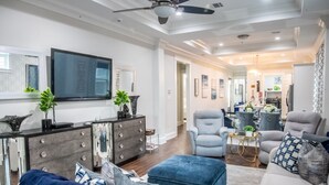 A modern living room with a flat-screen TV, grey armchairs, a sofa, and a coffee table. - Mid City Gorgeous Custom 4/3 one block from Street Car (New Orleans)