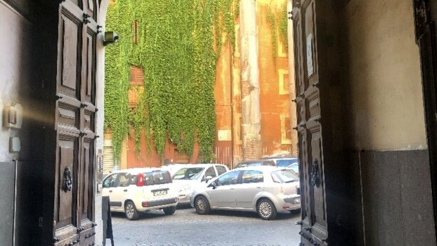An arched doorway leading to a cobblestone street with parked cars and a building covered in ivy. - PANTHEON Maison, in the center of Rome + breakfast included (Roma)