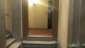 A narrow hallway with a wooden door at the end, a small step leading to a tiled floor, and a potted plant on the right. - PANTHEON Maison, in the center of Rome + breakfast included (Roma)