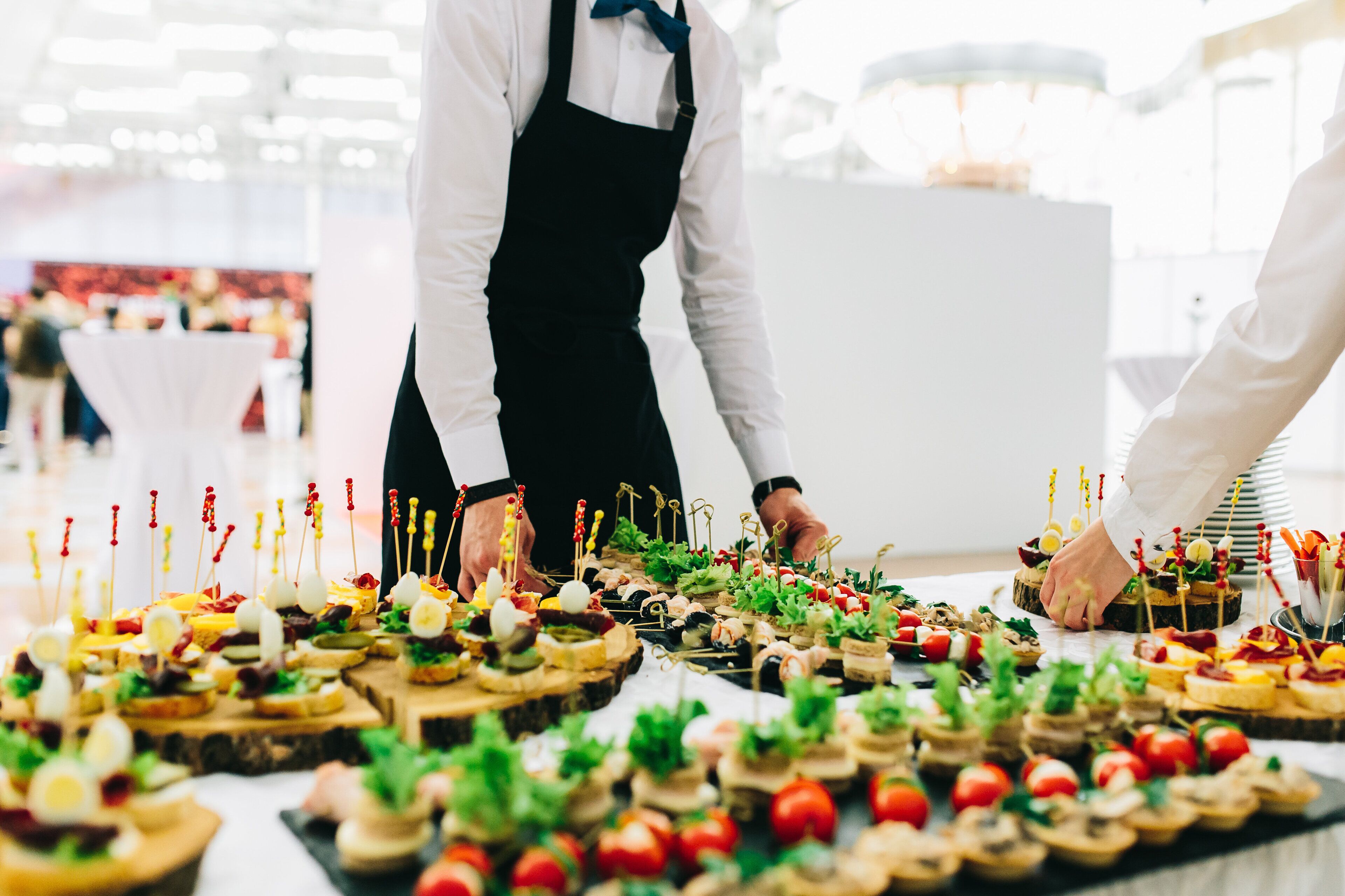 A buffet table with various appetizers arranged on wooden boards, attended by waitstaff.
