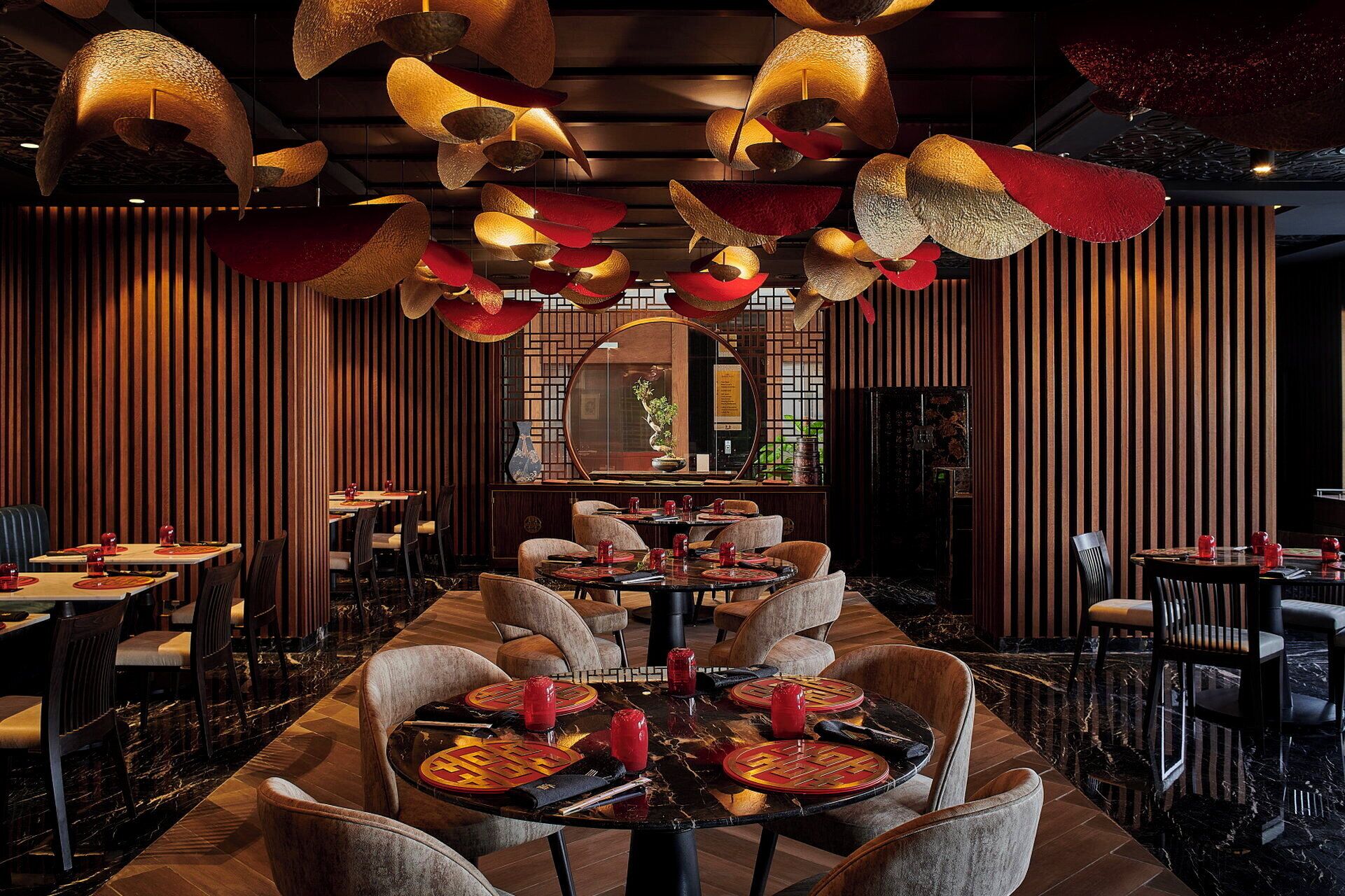 Interior de restaurante con mesas redondas, sillas y lámparas colgantes.