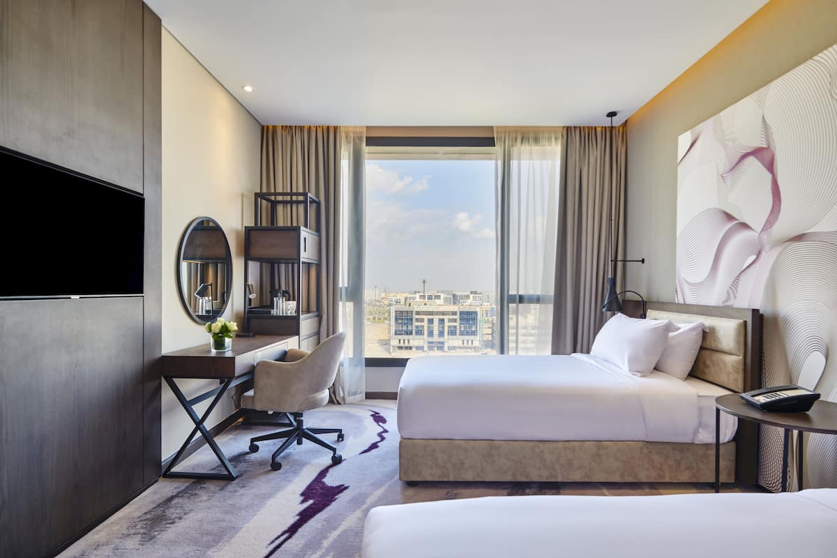 Une chambre d’hôtel avec un grand lit, un bureau avec une chaise, une télévision et une vue sur la ville.