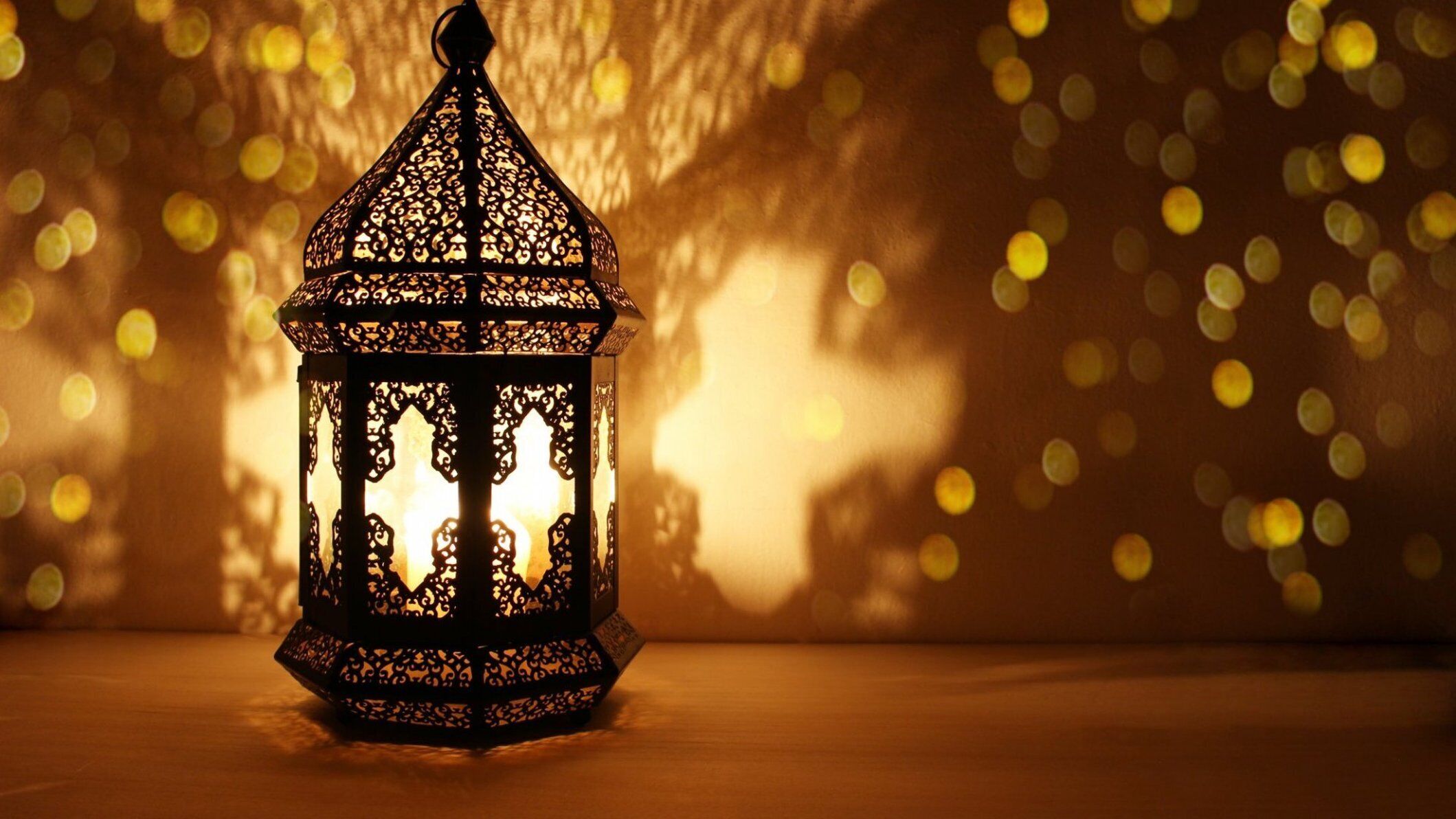 A lantern with intricate patterns, placed on a surface with a blurred background of lights.