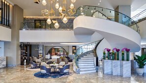 A spacious lobby with a marble floor, a curved staircase, and modern lighting fixtures. - Crowne Plaza West Cairo Arkan by IHG (Sheikh Zayed City)