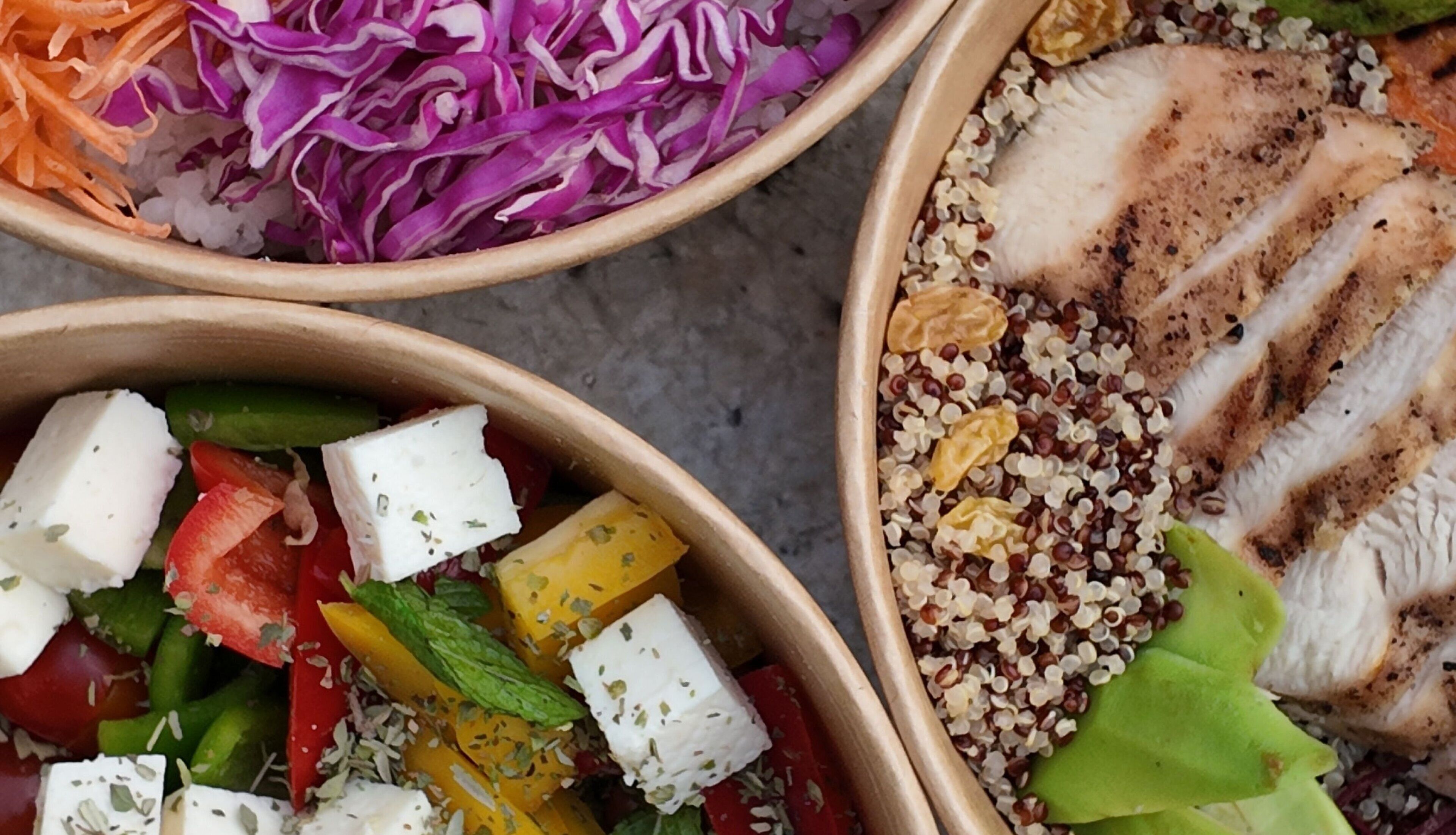 Three bowls with various salads and grilled chicken.