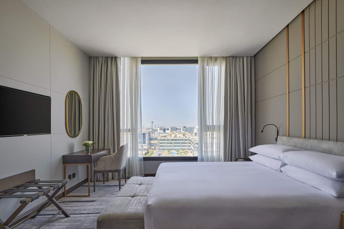 Une chambre d’hôtel moderne équipée d’un grand lit, d’un bureau, d’une chaise et d’un téléviseur.