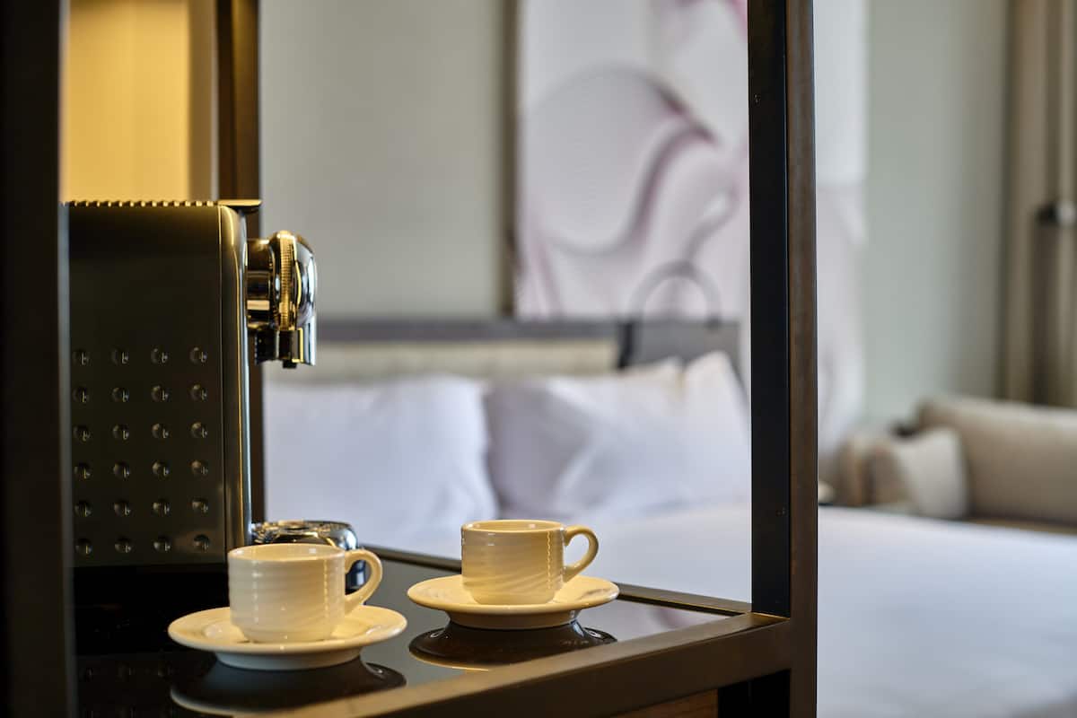 Une machine à café et deux tasses sur un plateau dans une chambre d’hôtel.
