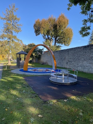 Explore the playground area surrounded by a vibrant mosaic and a serene natural setting.