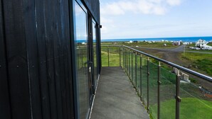 Un balcon offrant une vue dégagée sur l’océan et un paysage rural.