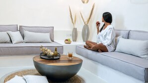 A modern living room with a grey sofa, a round coffee table with decorative items, and a vase with pampas grass.
