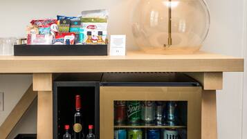A minibar with snacks, a bottle of Fiji water, and a variety of alcoholic beverages.