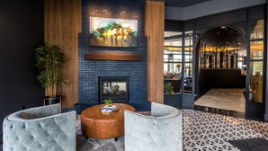 A modern lobby with a brick fireplace, two cushioned seating areas, and a large abstract painting on the wall.