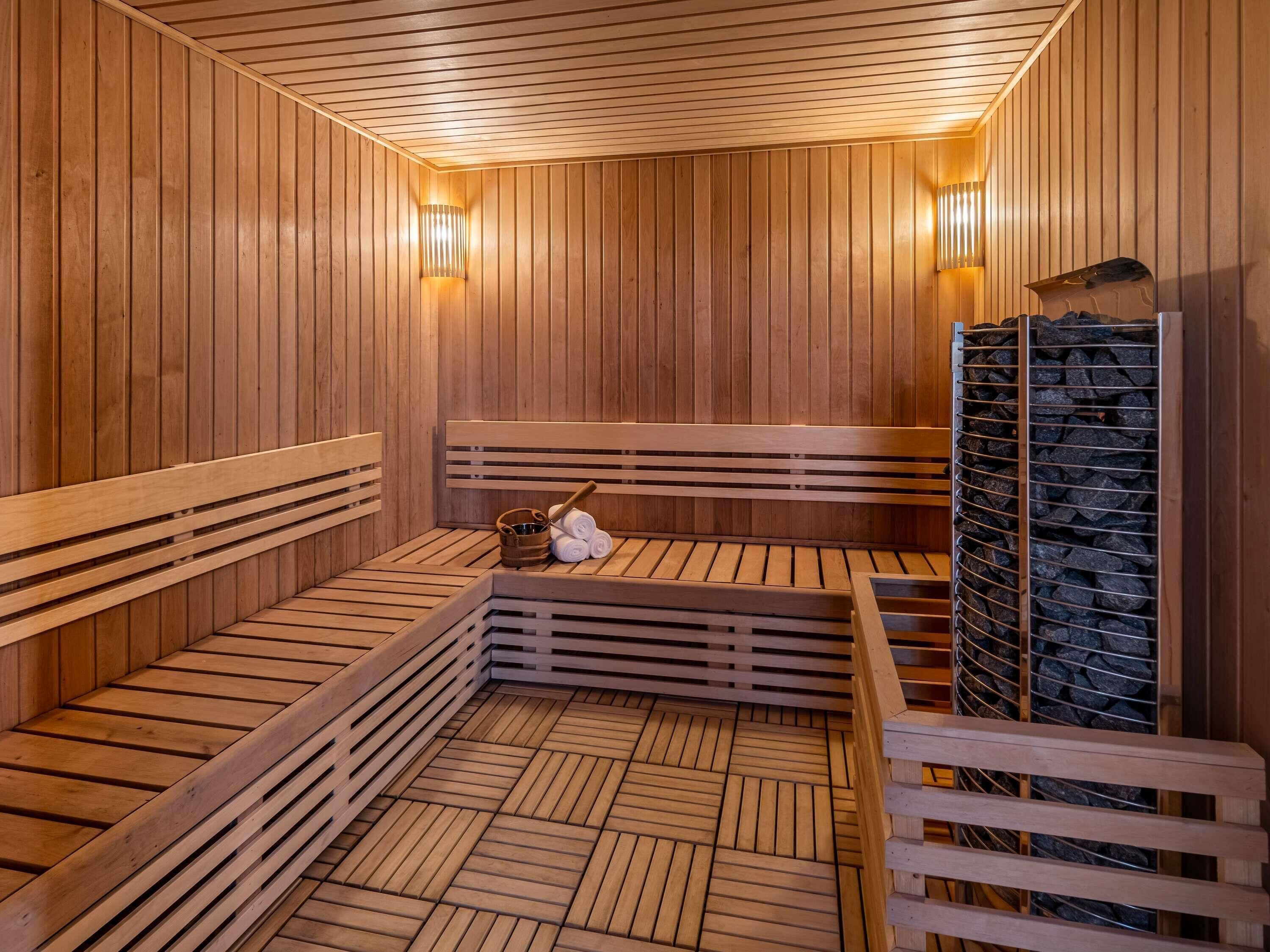 A sauna with wooden benches, a stone heater, and a wooden wall.