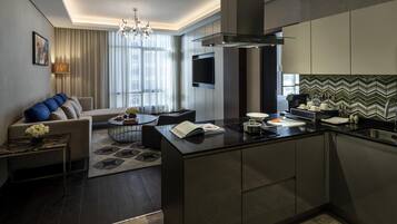 Una cocina moderna con una isla central, suelo de madera oscura y una zona de comedor con sofá y mesa de centro.