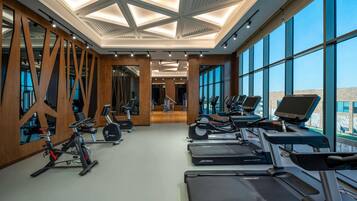 Un gimnasio con cintas de correr, bicicletas estáticas y un espejo grande.