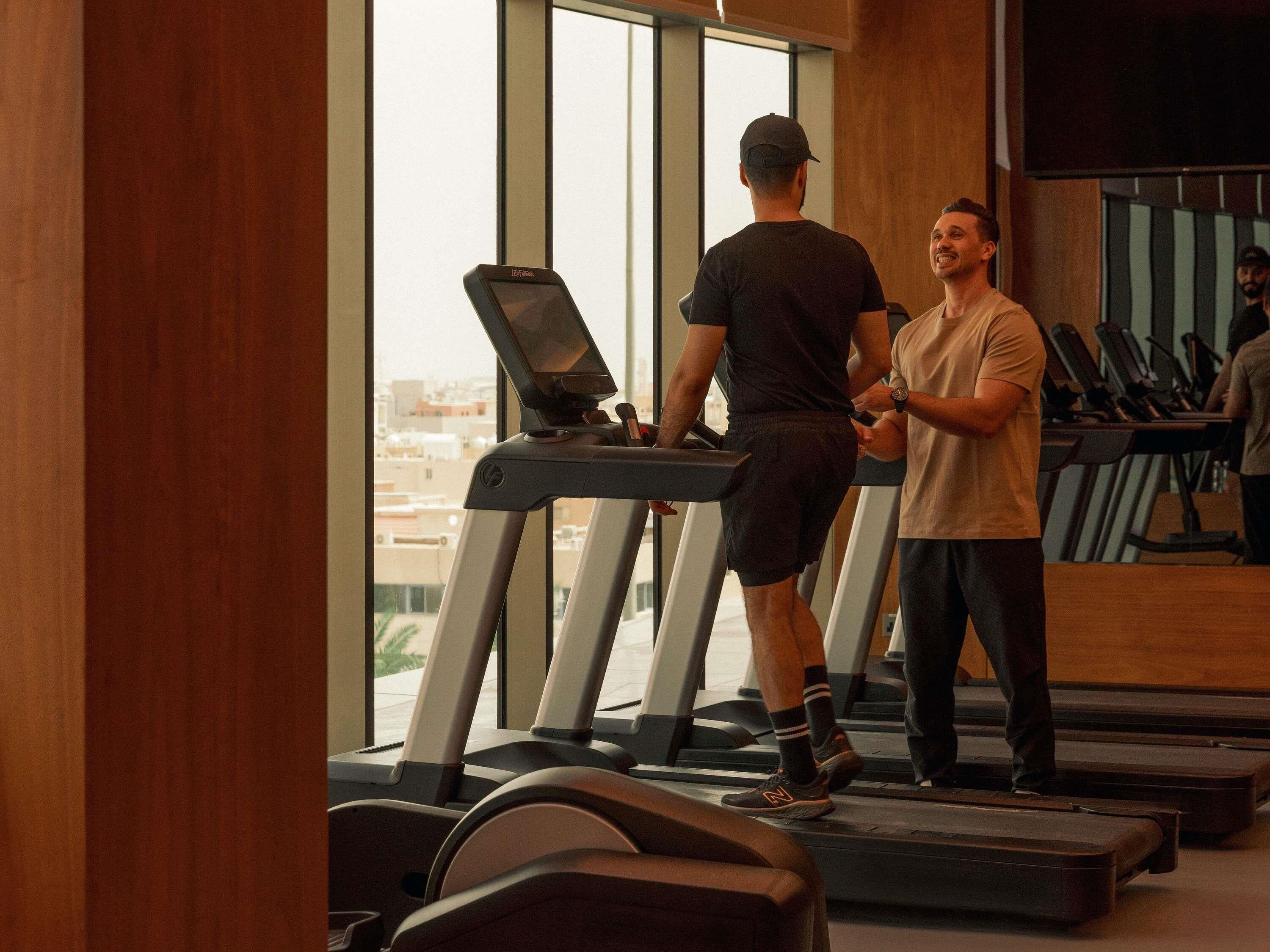 A gym with treadmills, a large window, and a city view.