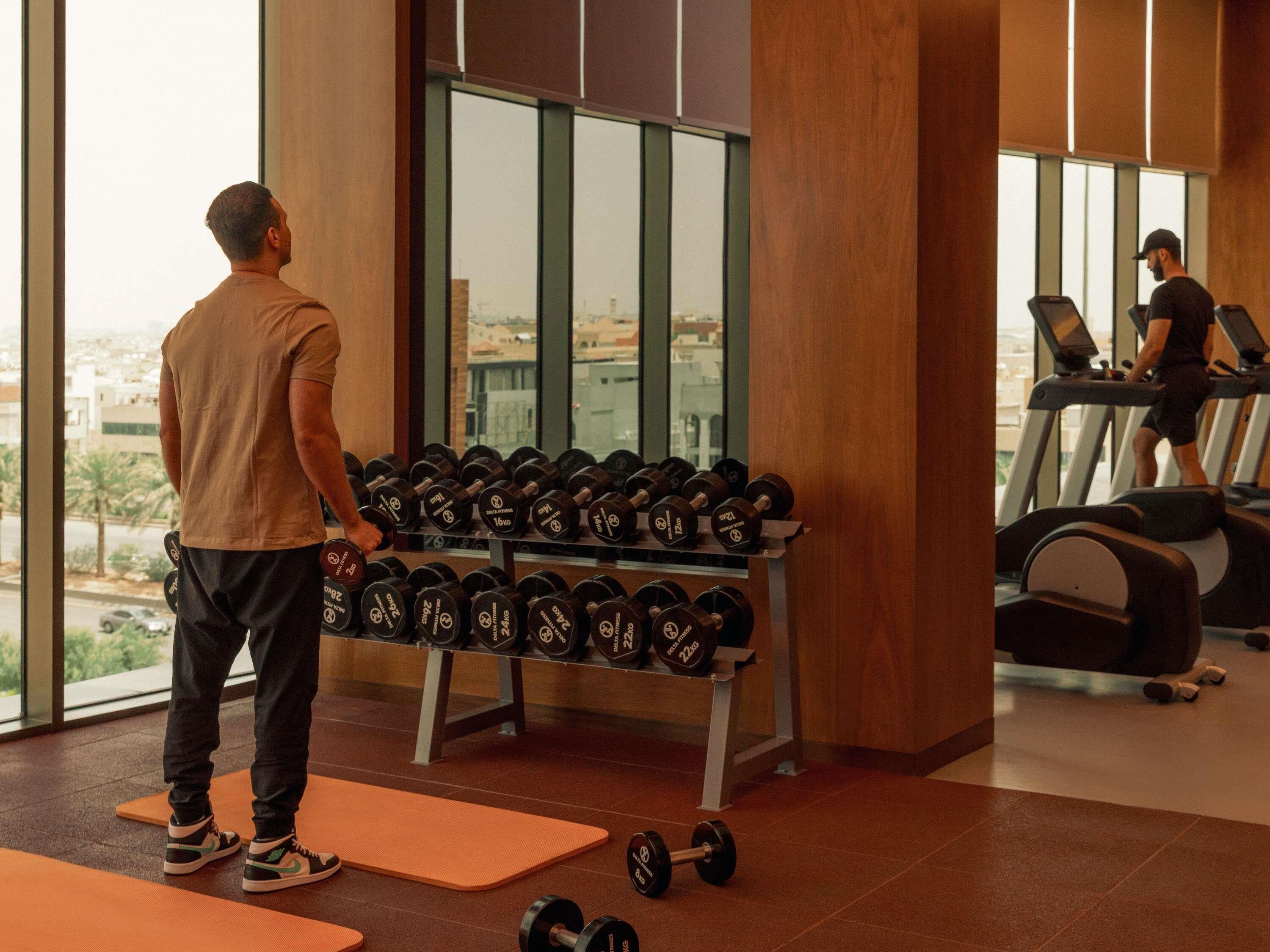 A gym with weightlifting equipment, treadmills, and orange mats.