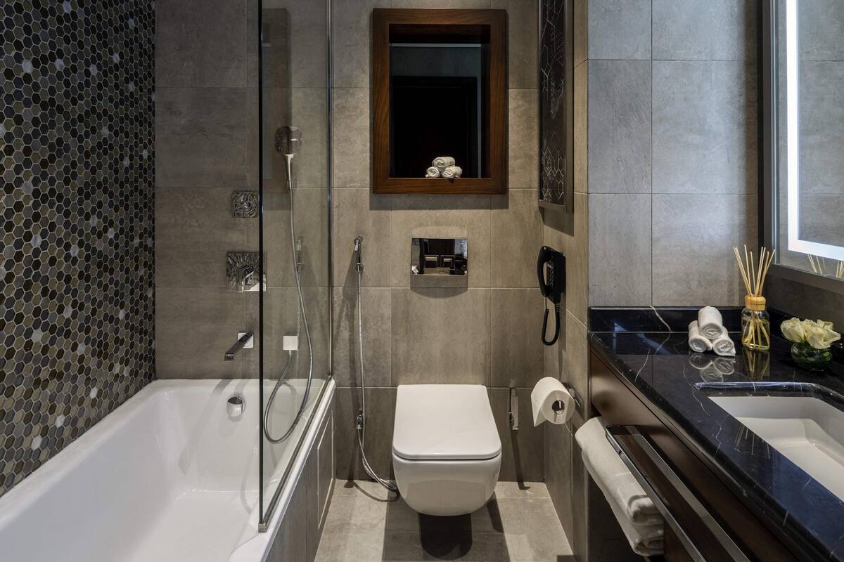 Ein modernes Badezimmer mit einer Glaskabine zur Dusche, einer Toilette und einem Waschtisch mit Spüle und Spiegel.