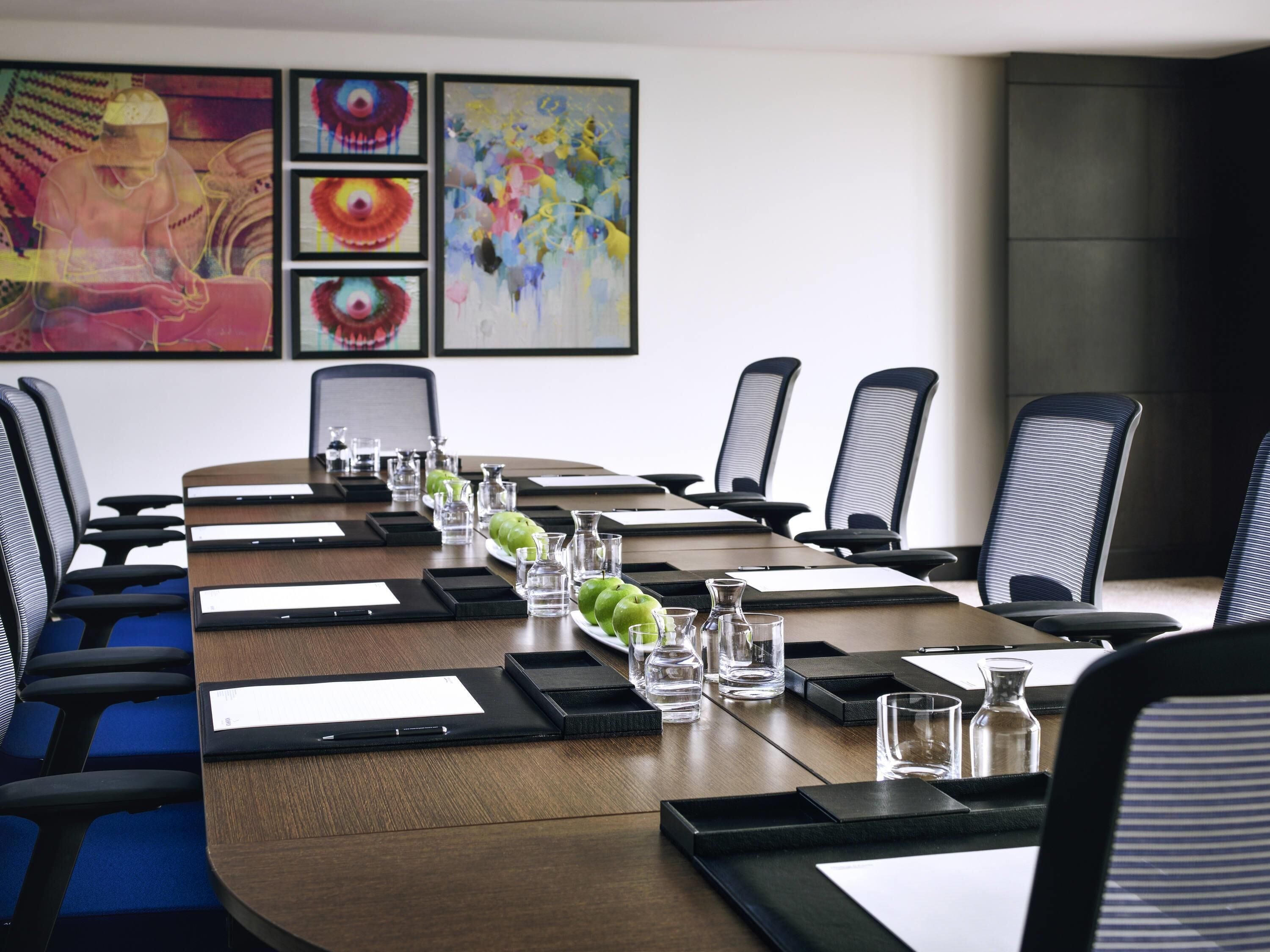 A conference room with a long table, chairs, and various items like water bottles and glasses.