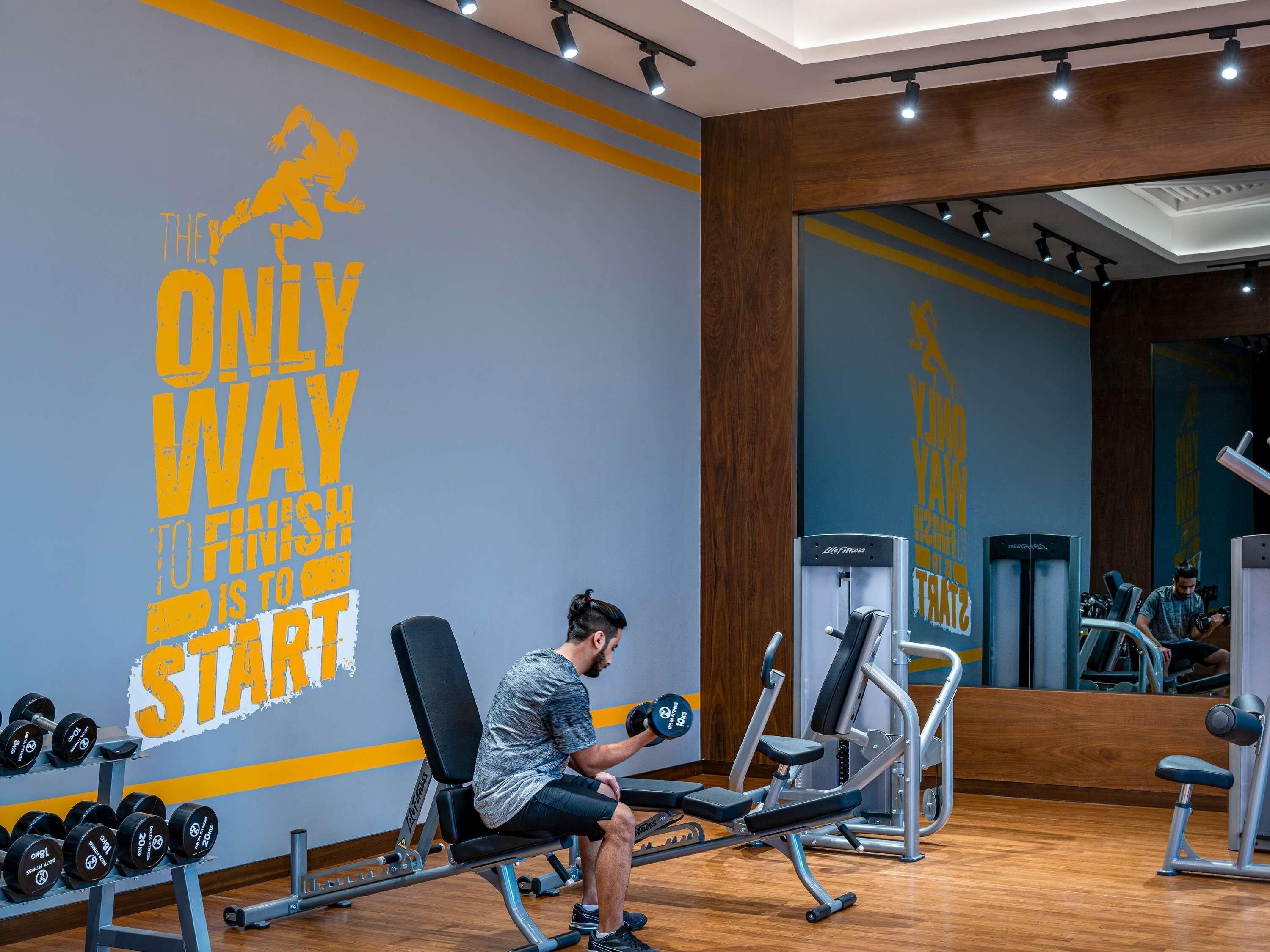 Une salle de sport dotée d’un mur d’inspiration, d’équipements d’haltérophilie et d’un miroir.